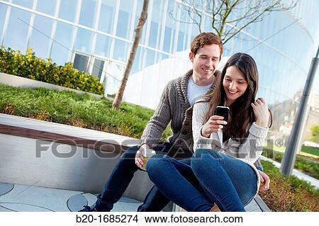 Young couple looking at mobile phone in the city, smartphone, Iberdrola Tower, Abandoibarra, Bilbao, Bizkaia, Basque Country, Spain View Large Photo Image Picture - Young couple looking at mobile phone in the city, smartphone, Iberdrola Tower, Abandoibarra, Bilbao, Bizkaia, Basque Country, Spain. Fotosearch