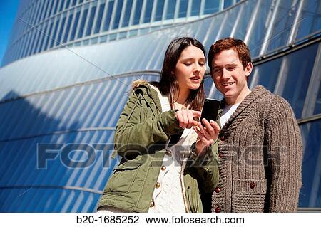 Young couple looking at mobile phone in the city, smartphone, Iberdrola Tower, Abandoibarra, Bilbao, Bizkaia, Basque Country, Spain View Large Photo Image Stock Image - Young couple looking at mobile phone in the city, smartphone, Iberdrola Tower, Abandoibarra, Bilbao, Bizkaia, Basque Country, Spain. Fotosearch