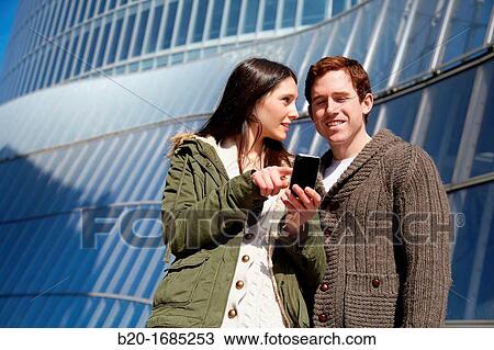 Young couple looking at mobile phone in the city, smartphone, Iberdrola Tower, Abandoibarra, Bilbao, Bizkaia, Basque Country, Spain View Large Photo Image Stock Image - Young couple looking at mobile phone in the city, smartphone, Iberdrola Tower, Abandoibarra, Bilbao, Bizkaia, Basque Country, Spain. Fotosearch