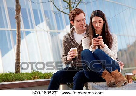 Young couple looking at mobile phone in the city, smartphone, Iberdrola Tower, Abandoibarra, Bilbao, Bizkaia, Basque Country, Spain View Large Photo Image Stock Image - Young couple looking at mobile phone in the city, smartphone, Iberdrola Tower, Abandoibarra, Bilbao, Bizkaia, Basque Country, Spain. Fotosearch
