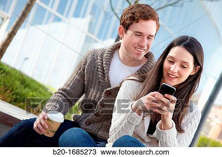 Stock Image - Young couple looking at mobile phone in the city, smartphone, Iberdrola Tower, Abandoibarra, Bilbao, Bizkaia, Basque Country, Spain. Fotosearch