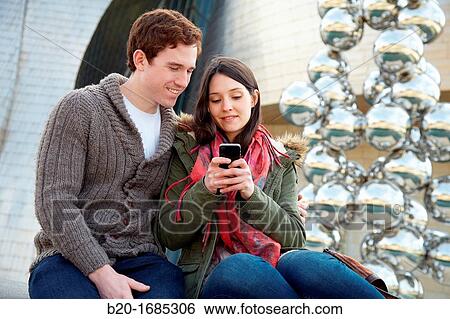 Young couple looking at mobile phone in the city, smartphone, Guggenheim Museum, Abandoibarra, Bilbao, Bizkaia, Basque Country, Spain View Large Photo Image Stock Photograph - Young couple looking at mobile phone in the city, smartphone, Guggenheim Museum, Abandoibarra, Bilbao, Bizkaia, Basque Country, Spain. Fotosearch