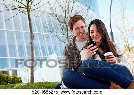 Young couple looking at mobile phone in the city, smartphone, Iberdrola Tower, Abandoibarra, Bilbao, Bizkaia, Basque Country, Spain View Large Photo Image Stock Photography - Young couple looking at mobile phone in the city, smartphone, Iberdrola Tower, Abandoibarra, Bilbao, Bizkaia, Basque Country, Spain. Fotosearch
