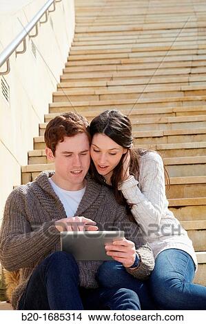 Young couple looking digital tablet in the city, digital tablet, Guggenheim Museum, Abandoibarra, Bilbao, Bizkaia, Basque Country, Spain View Large Photo Image Picture - Young couple looking digital tablet in the city, digital tablet, Guggenheim Museum, Abandoibarra, Bilbao, Bizkaia, Basque Country, Spain. Fotosearch