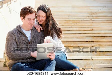 Young couple looking digital tablet in the city, digital tablet, Guggenheim Museum, Abandoibarra, Bilbao, Bizkaia, Basque Country, Spain View Large Photo Image Stock Image - Young couple looking digital tablet in the city, digital tablet, Guggenheim Museum, Abandoibarra, Bilbao, Bizkaia, Basque Country, Spain. Fotosearch