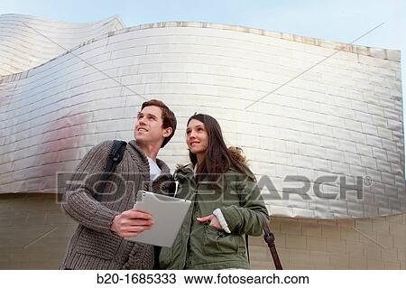 Young couple looking digital tablet in the city, digital tablet, Guggenheim Museum, Abandoibarra, Bilbao, Bizkaia, Basque Country, Spain View Large Photo Image Stock Image - Young couple looking digital tablet in the city, digital tablet, Guggenheim Museum, Abandoibarra, Bilbao, Bizkaia, Basque Country, Spain. Fotosearch
