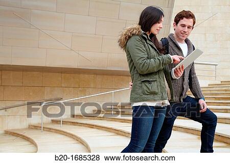 Young couple looking digital tablet in the city, digital tablet, Guggenheim Museum, Abandoibarra, Bilbao, Bizkaia, Basque Country, Spain View Large Photo Image Stock Photo - Young couple looking digital tablet in the city, digital tablet, Guggenheim Museum, Abandoibarra, Bilbao, Bizkaia, Basque Country, Spain. Fotosearch