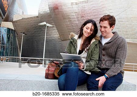 Stock Photography - Young couple looking digital tablet in the city, digital tablet, Guggenheim Museum, Abandoibarra, Bilbao, Bizkaia, Basque Country, Spain. Fotosearch