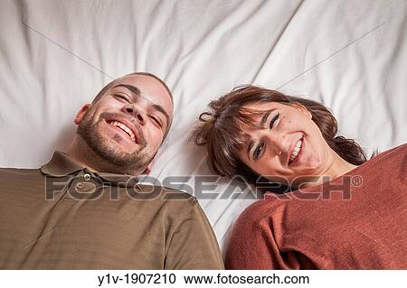 Stock Image - Young couple lying on a bed. Fotosearch