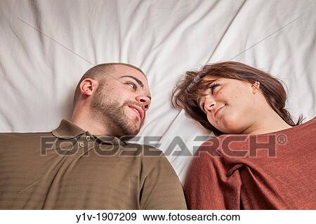 Stock Photo - Young couple lying on a bed. Fotosearch