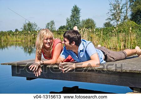 Young couple lying on a footbridge at a lake, Germany, Europe View Large Photo Image Stock Image - Young couple lying on a footbridge at a lake, Germany, Europe. Fotosearch