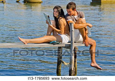 Young couple on a wooden pier View Large Photo Image Stock Image - Young couple on a wooden pier. Fotosearch