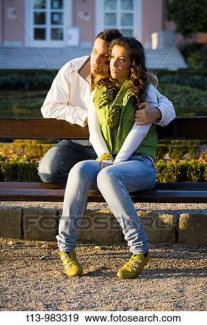 Young couple on wooden park bench during sunset View Large Photo Image Stock Photo - Young couple on wooden park bench during sunset. Fotosearch