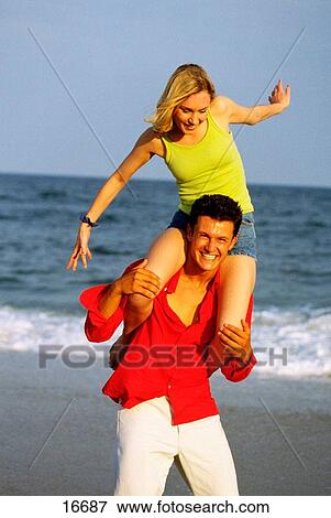 Stock Photo - Young couple playing on beach. Fotosearch