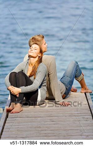 Picture - Young couple relaxing, sitting in a Pier in Wansee, Berlin. Fotosearch