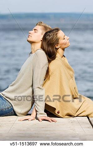 Stock Photo - Young couple relaxing, sitting in a Pier in Wansee, Berlin. Fotosearch