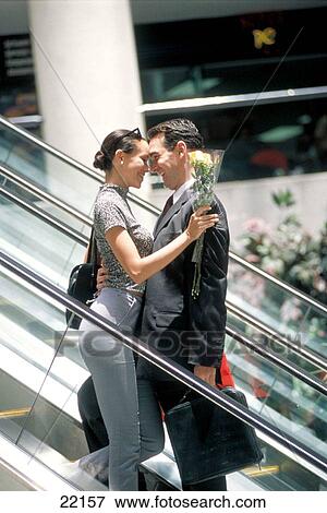 Young couple sharing a romantic moment while moving on an escalator at shopping mall View Large Photo Image Stock Photo - Young couple sharing a romantic moment while moving on an escalator at shopping mall. Fotosearch