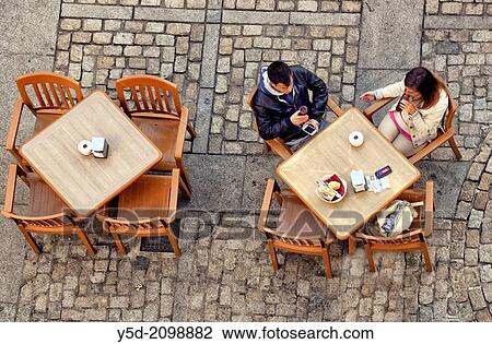Stock Image - young couple sitting at the outside coffe table, view from above, Cathedral square, Cadiz, Andalusia, Spain. Fotosearch