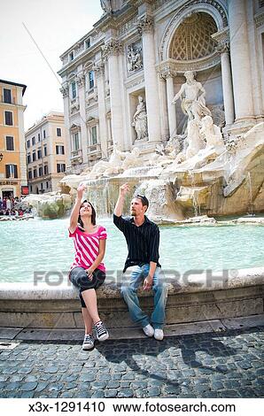 Young couple sitting at Trevi Fountain in Rome, Italy View Large Photo Image Stock Image - Young couple sitting at Trevi Fountain in Rome, Italy. Fotosearch