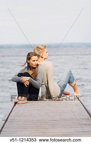 Stock Image - Young couple sitting in a pier. Fotosearch