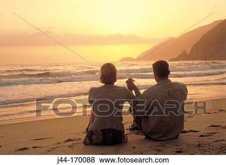 Young couple sitting in the sand holding hands and looking the sunset at the beach, Venezuela View Large Photo Image Stock Photo - Young couple sitting in the sand holding hands and looking the sunset at the beach, Venezuela. Fotosearch