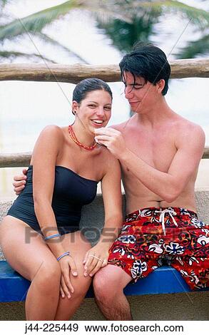Young couple sitting on a bench sharing a snack at the beach View Large Photo Image Stock Photo - Young couple sitting on a bench sharing a snack at the beach. Fotosearch