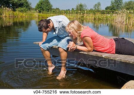 Young couple sitting on a footbridge at a lake View Large Photo Image Stock Photograph - Young couple sitting on a footbridge at a lake. Fotosearch