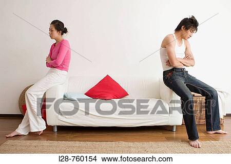 Young couple sitting on opposite ends of the sofa View Large Photo Image Picture - Young couple sitting on opposite ends of the sofa. Fotosearch