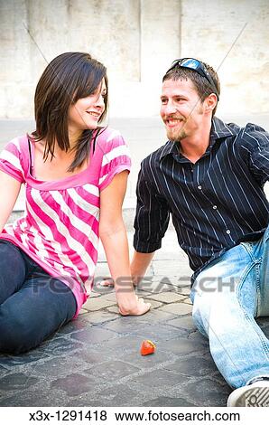Young couple sitting on sidewalk with strawberry on ground View Large Photo Image Stock Photo - Young couple sitting on sidewalk with strawberry on ground. Fotosearch
