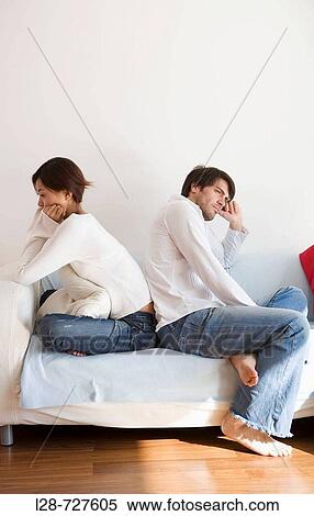 Stock Photography - Young Couple sitting on sofa. Fotosearch
