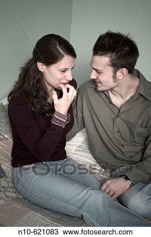 Young couple sitting on their bed. View Large Photo Image Stock Image - Young couple sitting on their bed.. Fotosearch