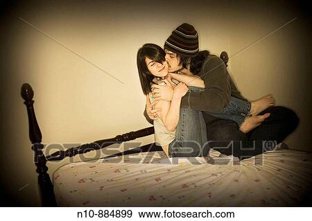 Stock Photo - Young couple sitting on their bed. Model and Property Released.. Fotosearch
