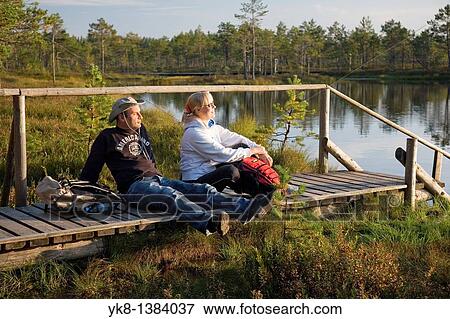 Young Couple Sitting on Wooden Boardwalk by Water in Meenikunno Landscape Reserve, Estonia View Large Photo Image Stock Photo - Young Couple Sitting on Wooden Boardwalk by Water in Meenikunno Landscape Reserve, Estonia. Fotosearch