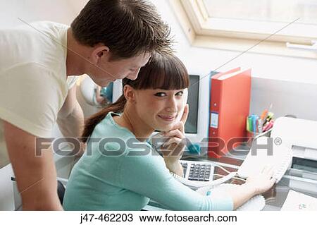 Young couple sitting together in the office she is on the phone and smiling at the camera View Large Photo Image Stock Image - Young couple sitting together in the office she is on the phone and smiling at the camera. Fotosearch