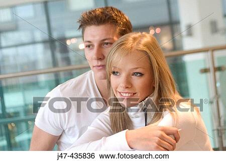 Young couple sitting together, looking off camera smiling View Large Photo Image Stock Photograph - Young couple sitting together, looking off camera smiling. Fotosearch