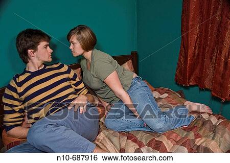 Young couple sitting together on their bed. View Large Photo Image Stock Photograph - Young couple sitting together on their bed.. Fotosearch