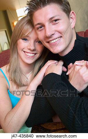 Young couple sitting together, smiling into camera in a bar View Large Photo Image Stock Image - Young couple sitting together, smiling into camera in a bar. Fotosearch