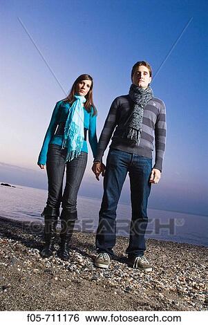 Young couple standing on the beach View Large Photo Image Stock Photograph - Young couple standing on the beach. Fotosearch