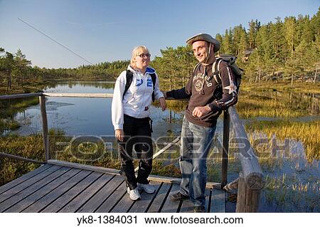 Stock Image - Young Couple Standing on Wooden Boardwalk in Meenikunno Bog by Water, Estonia. Fotosearch