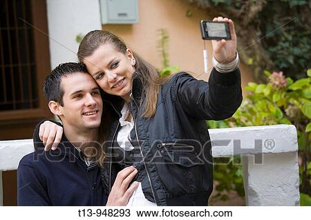 Stock Image - Young couple taking photo a with cellular phone. Fotosearch