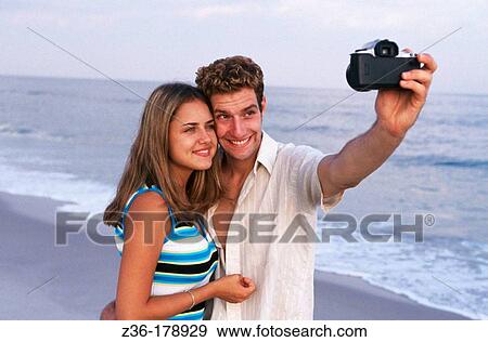 Young couple taking self-portrait with camera View Large Photo Image Stock Photo - Young couple taking self-portrait with camera. Fotosearch