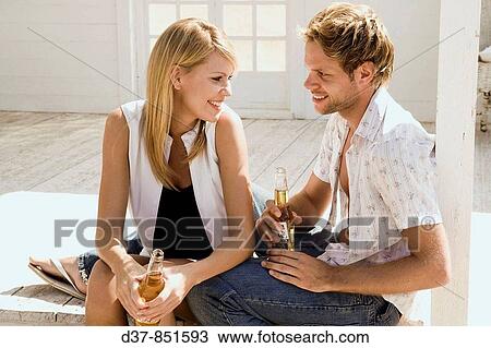 Young couple talking and drinking a beer View Large Photo Image Stock Image - Young couple talking and drinking a beer. Fotosearch