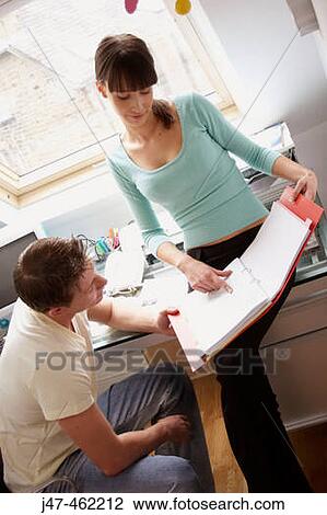 Stock Image - Young couple together in the office looking at a file, smiling. Fotosearch