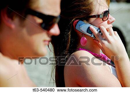 young couple together on beach, woman on cell phone View Large Photo Image Stock Image - young couple together on beach, woman on cell phone. Fotosearch