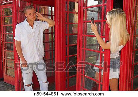 Young couple using mobile phones around a row of British public phone boxes. View Large Photo Image Stock Image - Young couple using mobile phones around a row of British public phone boxes.. Fotosearch