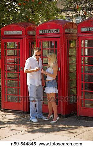 Young couple using mobile phones on street next to row of British public phone boxes. View Large Photo Image Stock Photography - Young couple using mobile phones on street next to row of British public phone boxes.. Fotosearch