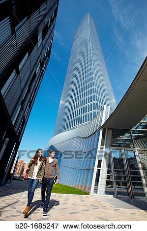 Young couple walking, Iberdrola Tower, designed by Cesar Pelli, Abandoibarra, Bilbao, Bizkaia, Basque Country, Spain View Large Photo Image Stock Photo - Young couple walking, Iberdrola Tower, designed by Cesar Pelli, Abandoibarra, Bilbao, Bizkaia, Basque Country, Spain. Fotosearch