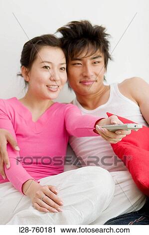 Stock Image - Young Couple watching movie on tv.. Fotosearch
