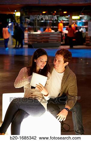 Stock Image - Young couple with digital tablet, digital tablet, Alhondiga building, leisure and culture center, Bilbao, Bizkaia, Basque Country, Spain. Fotosearch