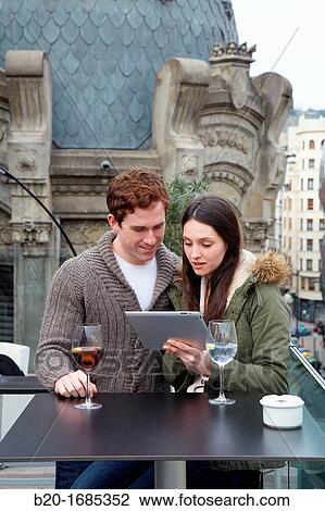 Stock Image - Young couple with digital tablet, digital tablet, Urban terrace bar, Alhondiga building, leisure and culture center, Bilbao, Bizkaia, Basque Country, Spain. Fotosearch